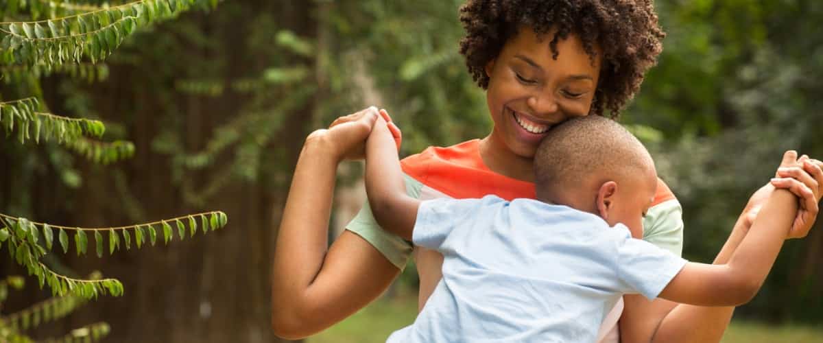 A smiling Black mother holds her toddler son