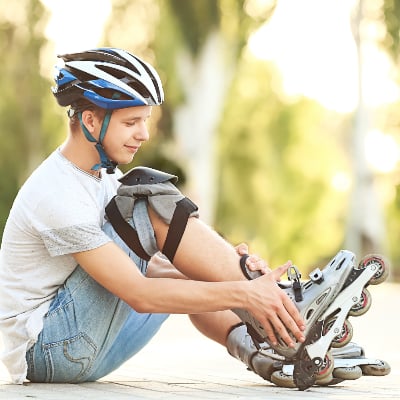 A teen boy adjusts his roller blades